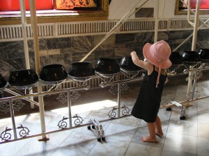 Emmy dropping coins in Monk's bowls at Wat Pho